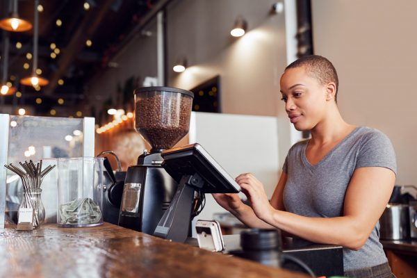 Female Coffee Shop Owner Working Behind Sales Desk
