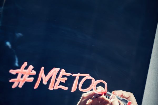 Girl writing "#metoo" on a mirror with a red lipstick.