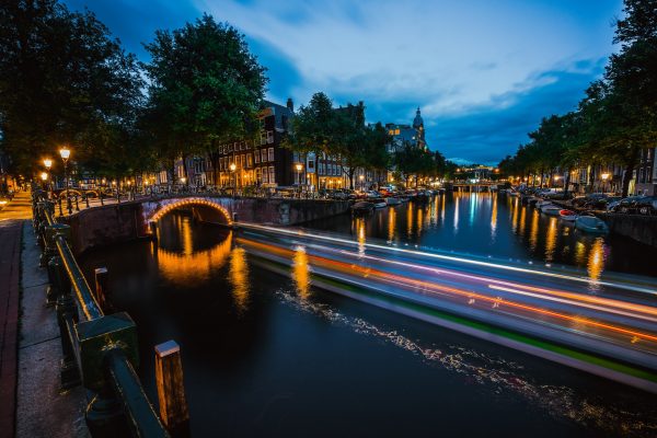 Night in Amsterdam. Lights trails and illuminated bridges on city canal at twilight. Holland