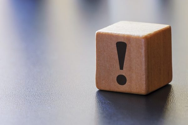 Warning exclamation mark on a wooden block